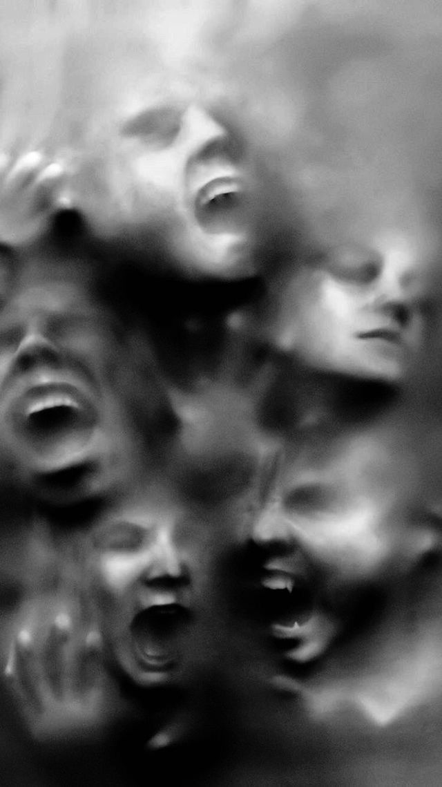 many faces are shown in black and white, with the background blurry from them