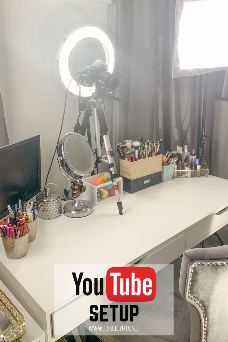 a white desk topped with a laptop computer next to a mirror and a light on top of it