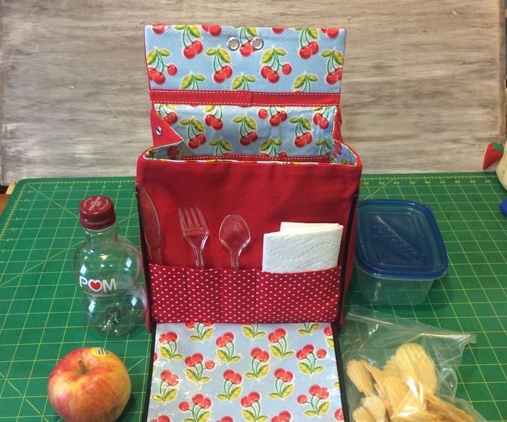 the contents of a lunch bag sitting on top of a cutting board next to an apple