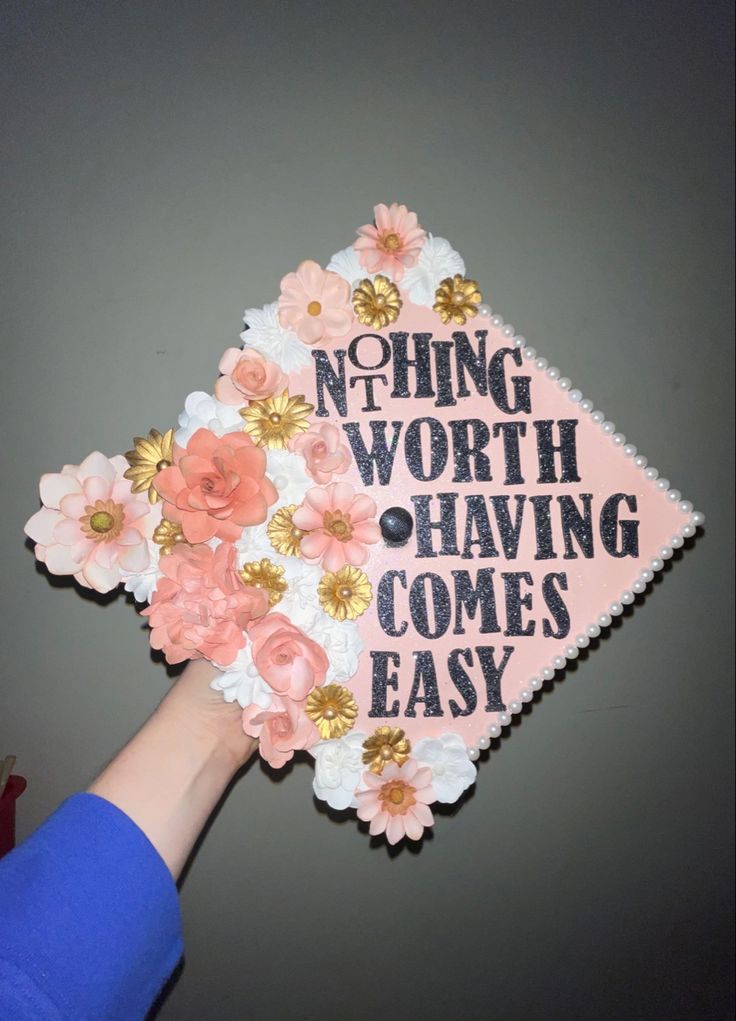 someone is holding up a pink and white graduation cap that says nothing worth having comes easy