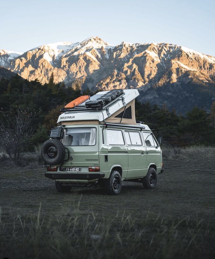 an old van with a camper attached to it parked in front of some mountains