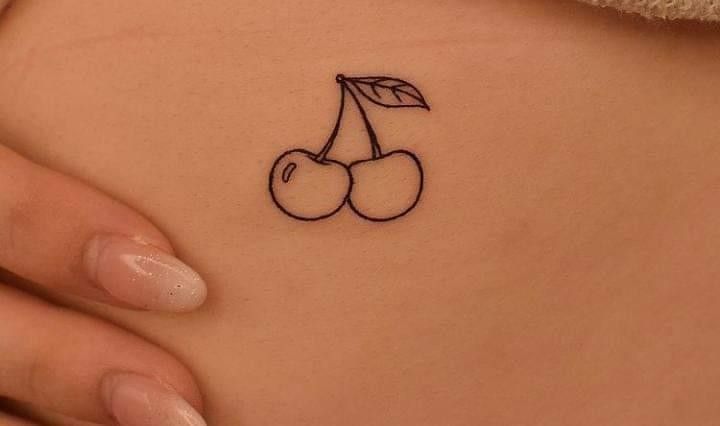 a woman's stomach with a small tattoo of two cherries on it