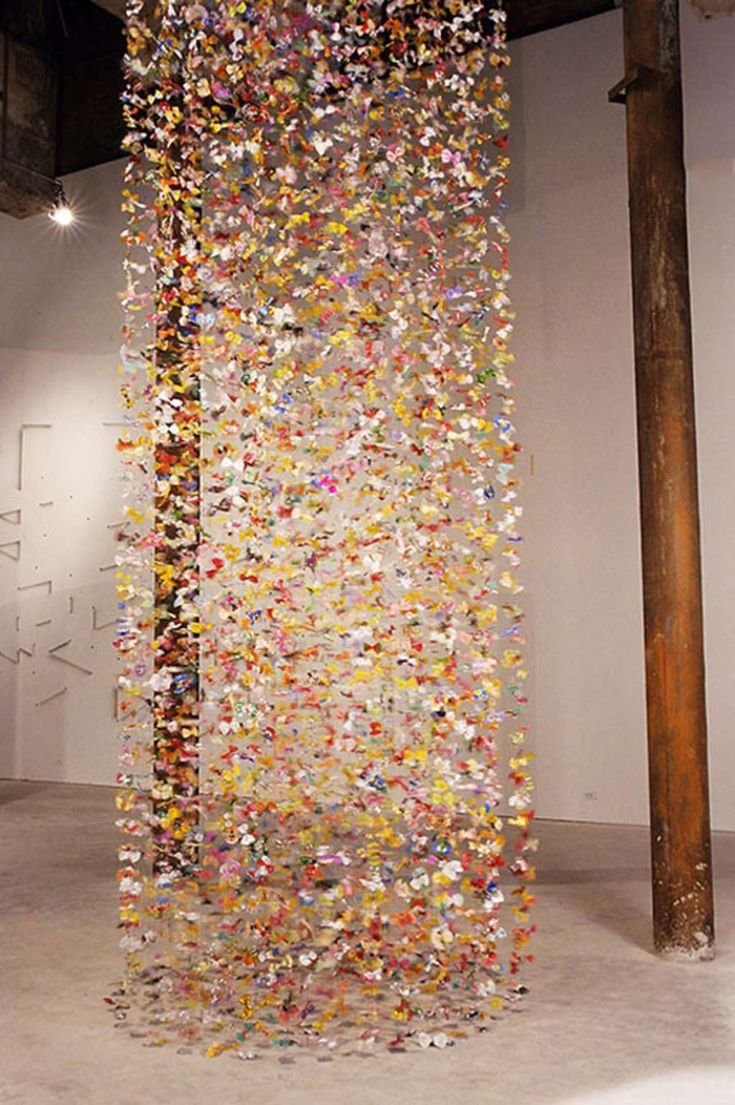 a tall sculpture made out of many different colored confetti on the wall and floor