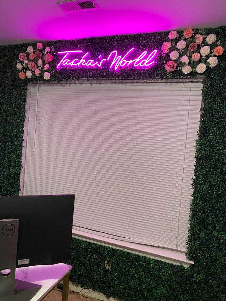 an office cubicle decorated with artificial flowers and greenery is lit up by neon lights