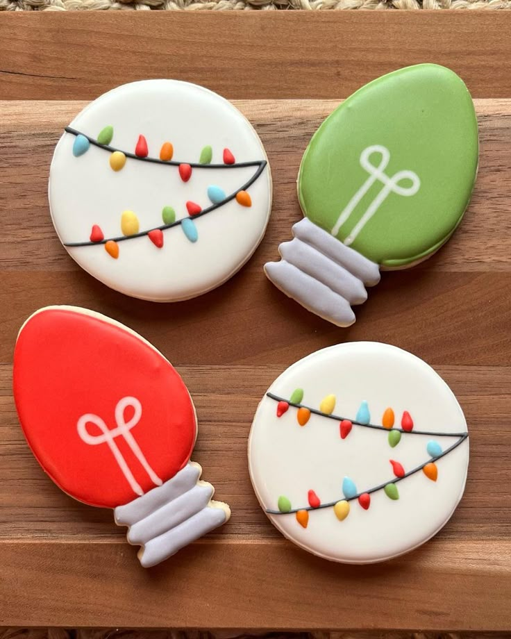 three decorated cookies sitting on top of a wooden table next to each other with string lights