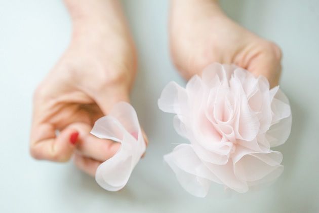 a person's bare feet and pink flower in their left hand on a white surface