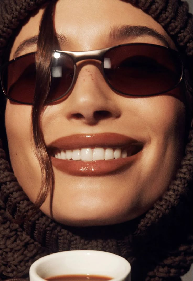 a woman wearing sunglasses and holding a cup of coffee