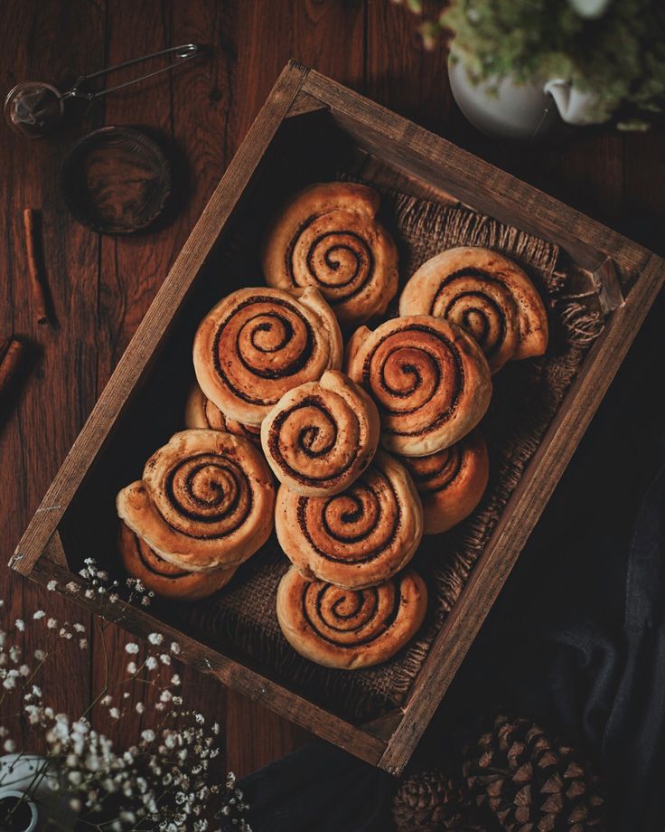 a wooden box filled with cinnamon rolls on top of a table