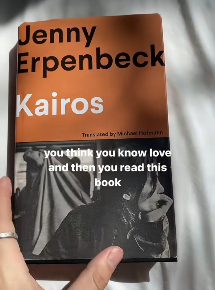 a person holding up a book about karios in front of a white sheet