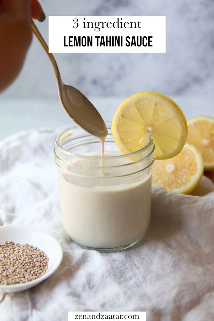 lemon tahiti sauce being poured into a glass jar with a spoon and sliced lemons in the background