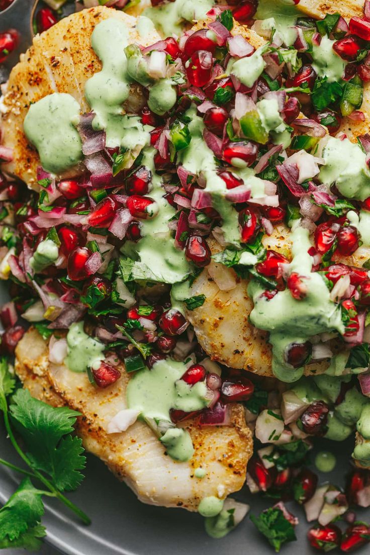 a plate topped with fish covered in guacamole and pomegranate