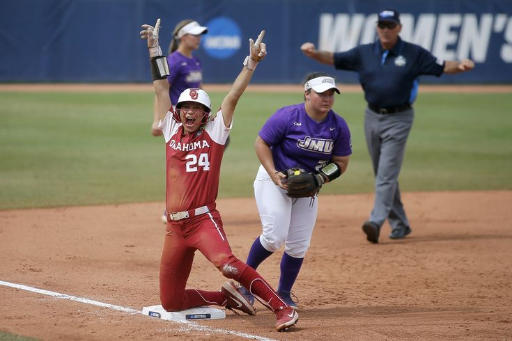 two female softball players are on the field and one is holding her hand up in the air