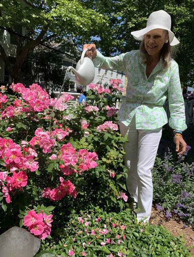 a woman is watering flowers in the garden