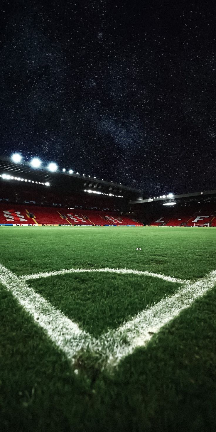 an empty soccer field at night with the lights on and stars in the sky above