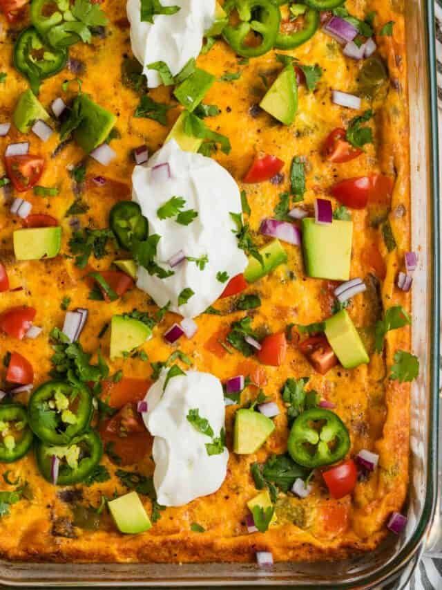 an enchilada casserole in a glass dish with sour cream on top