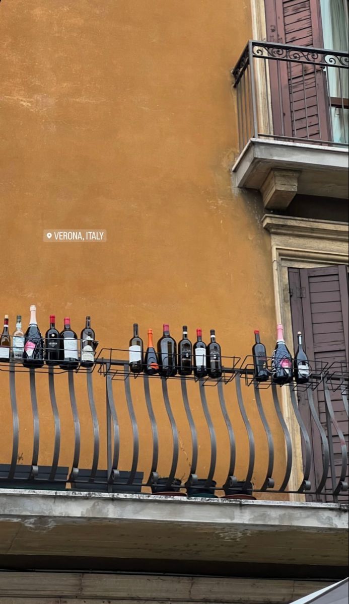 several bottles of wine are lined up on a balcony railing in front of a building