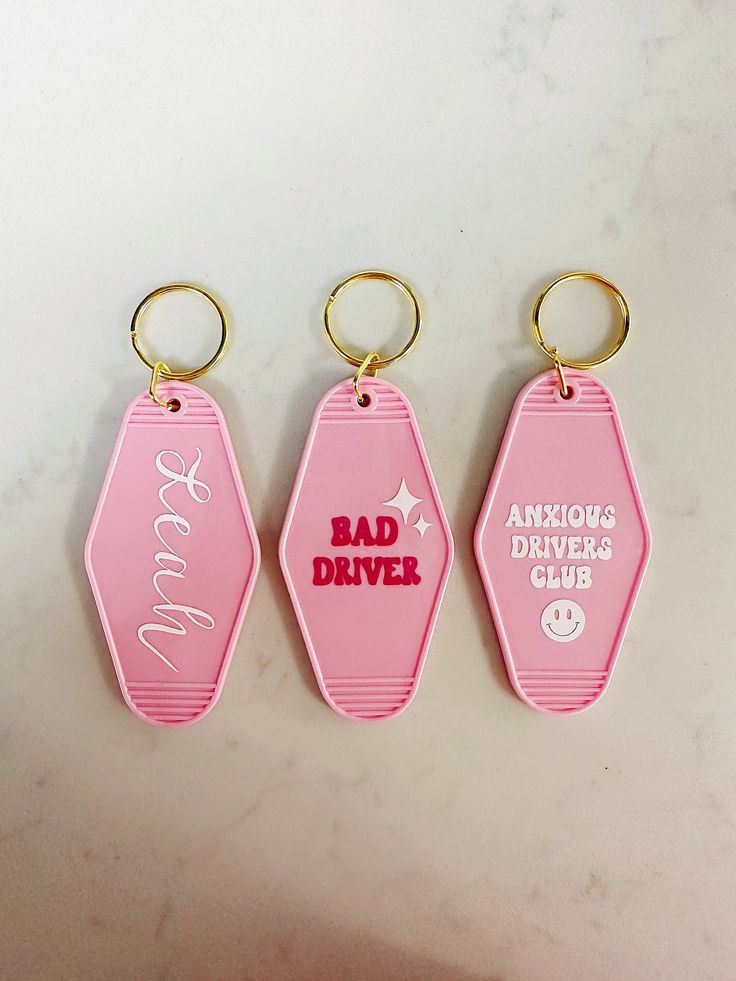 three pink key chains with the words bad driver and angry drivers club written on them