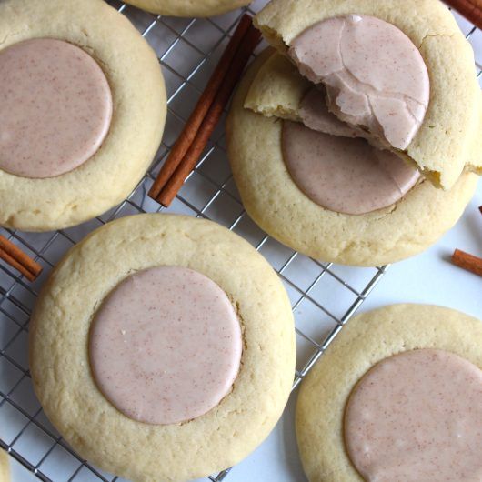 several cookies with frosting and cinnamon sticks on a cooling rack next to each other