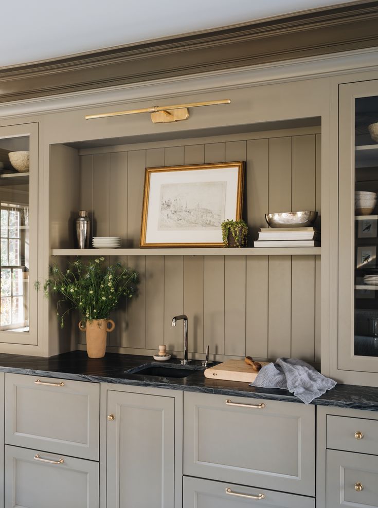 a kitchen with white cabinets and black counter tops in front of a painting on the wall