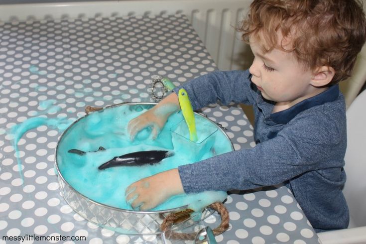 a little boy that is sitting at a table with some kind of blue substance on it