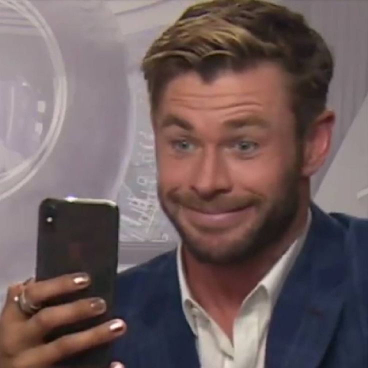 a man in a blue suit is holding a cell phone and smiling at the camera