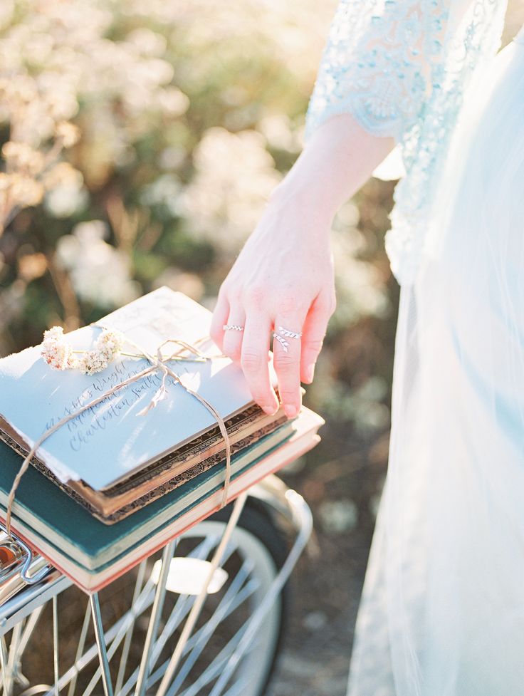 a woman holding a stack of books on top of a bike