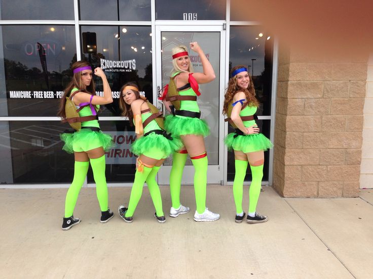 four girls dressed in green and brown posing for the camera outside a store front window