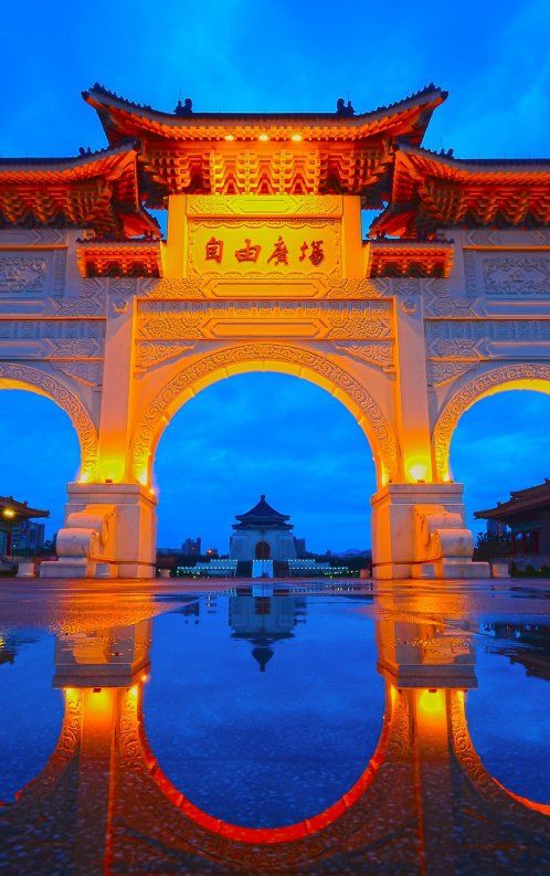 an archway lit up at night with lights reflecting in the water