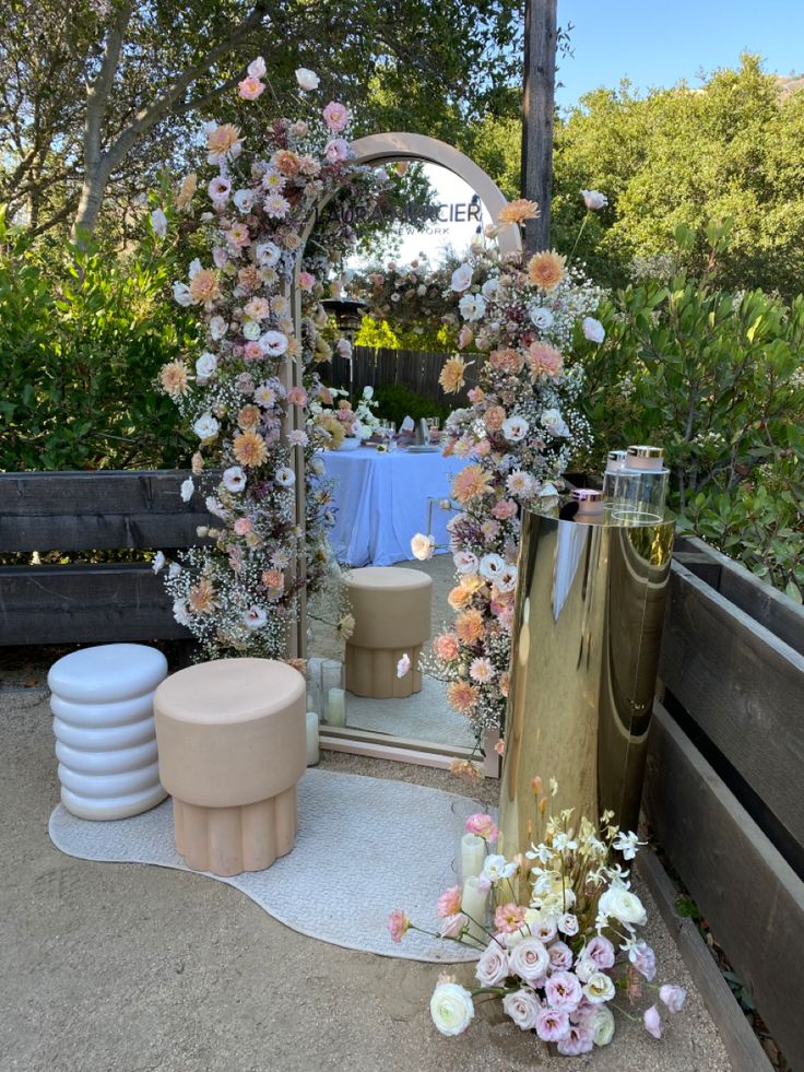 there is a mirror and some flowers on the ground in front of a wooden bench