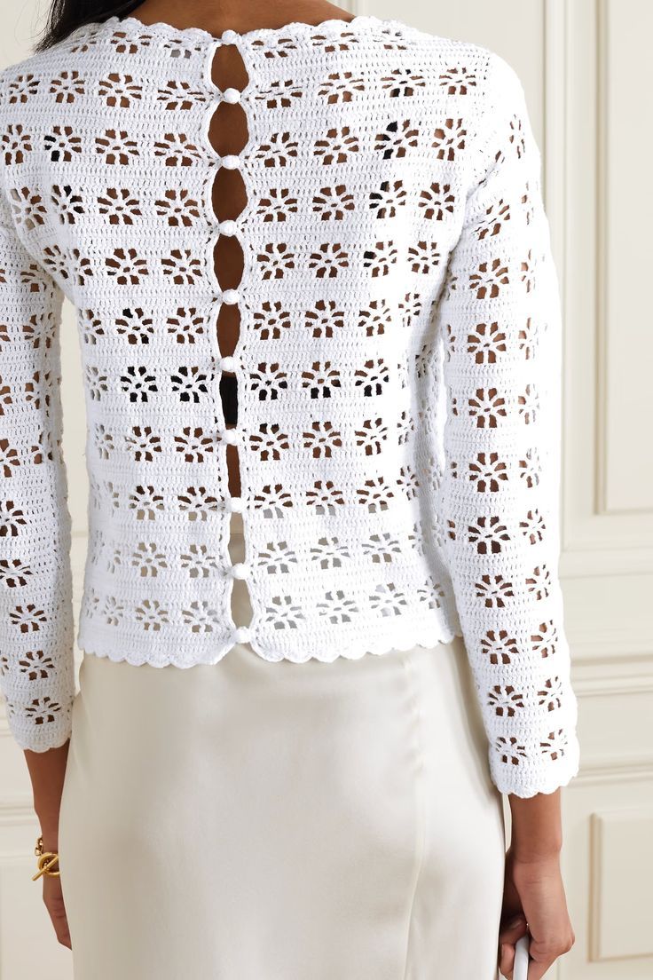 a woman wearing a white crochet jacket with an openwork design on the back