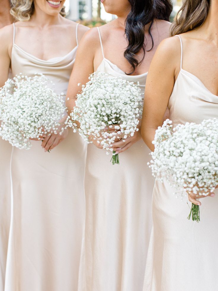 bridesmaids in white dresses holding bouquets of baby's breath