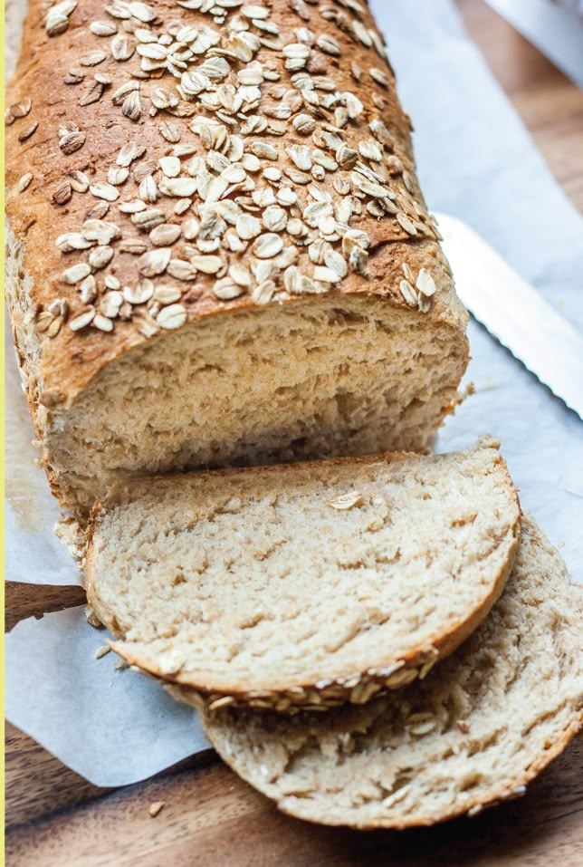 a loaf of bread sitting on top of a wooden cutting board next to sliced bread