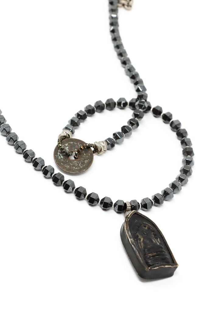 The Mya Lambrecht Buddha Necklace is minimal yet striking! Material: Natural stones, metalOrigin: Made in Minnesota Hook closure Handmade sitting Buddha from Thailand Ancient Chinese I-Ching coin Hematite 28" long Mya Lambrecht incorporates everyday objects into her pieces that are seemingly out of place. Her pieces create a relationship between people and the earth. Spiritual Single Strand Long Necklace, Spiritual One-of-a-kind Metal Necklace, Oxidized Pendant For Meditation, Spiritual Black Coin Pendant Jewelry, Artisan Medallion Necklace For Meditation, Black Spiritual Jewelry With Coin Pendant, Oxidized Finish Pendant For Meditation, Spiritual Oxidized Finish Jewelry For Meditation, Natural Stones Medallion Amulet Jewelry