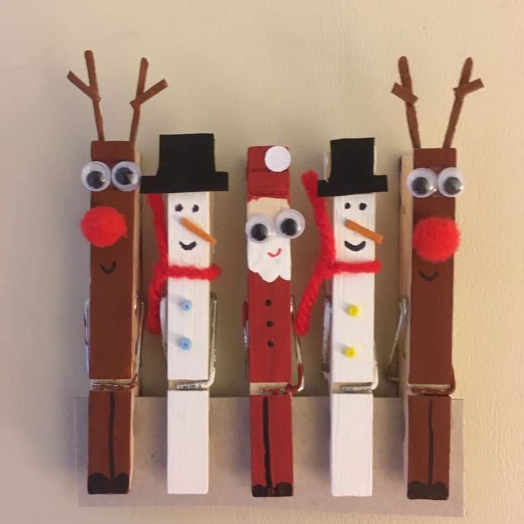 three snowmen made out of toilet paper tubes on a white wall with one wearing a top hat and the other wearing a red scarf