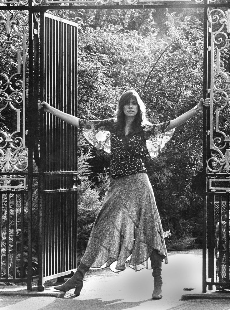 a woman standing in front of an iron gate with her arms outstretched and legs spread out