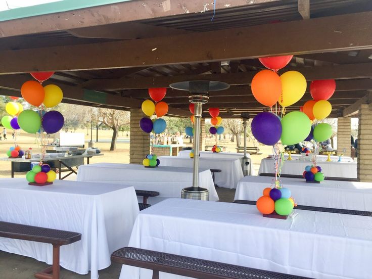 tables with white tablecloths and colorful balloons on them