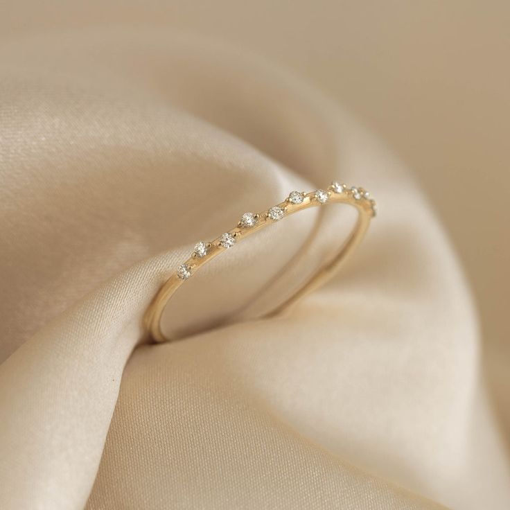 a diamond ring sitting on top of a white satin material with the fabric in the background