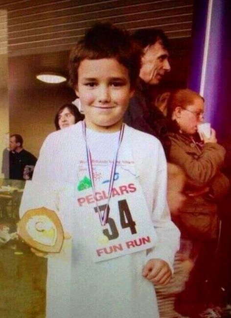 a young boy standing in front of a group of people wearing numbers on their shirts