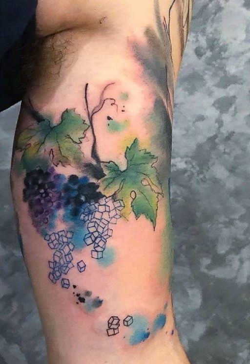 a man with a watercolor tattoo on his arm holding a wine bottle and grapes