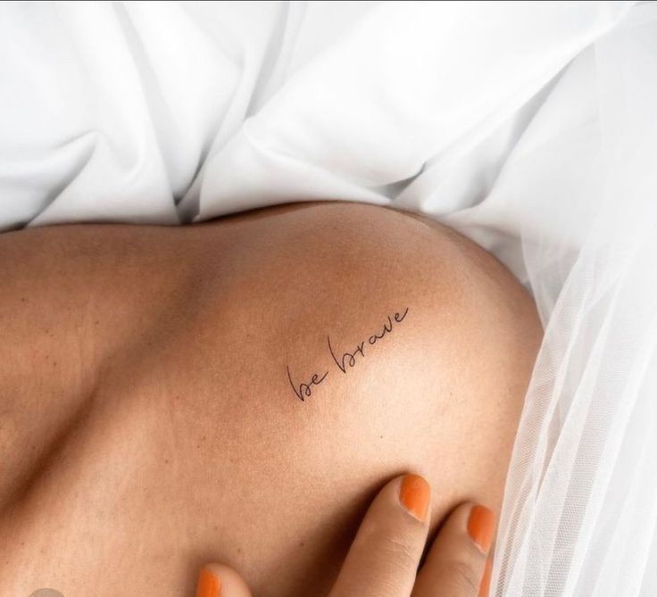 a woman's back with the word love written on her left side, in cursive font