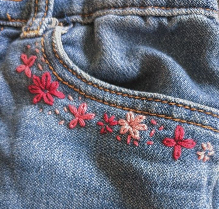 the back pocket of a pair of jeans with embroidered flowers on it and stitching