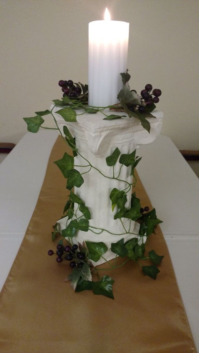 a candle that is sitting on top of a table with ivy and leaves around it