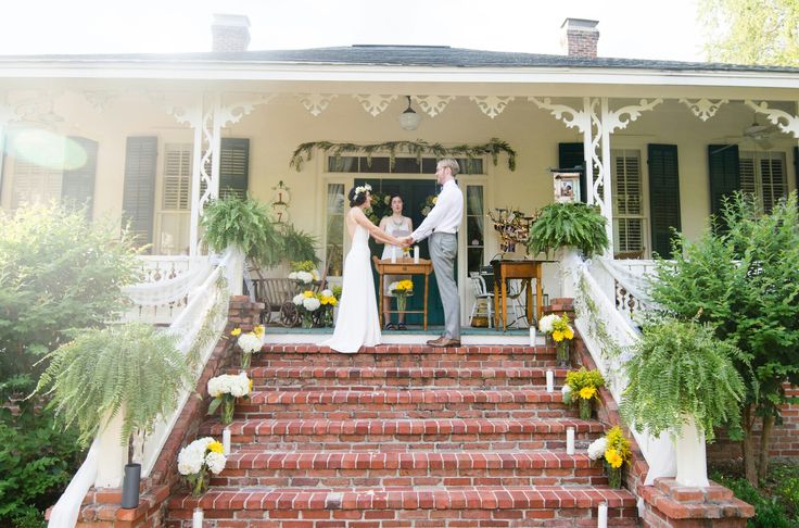 a bride and groom standing on the steps of a house