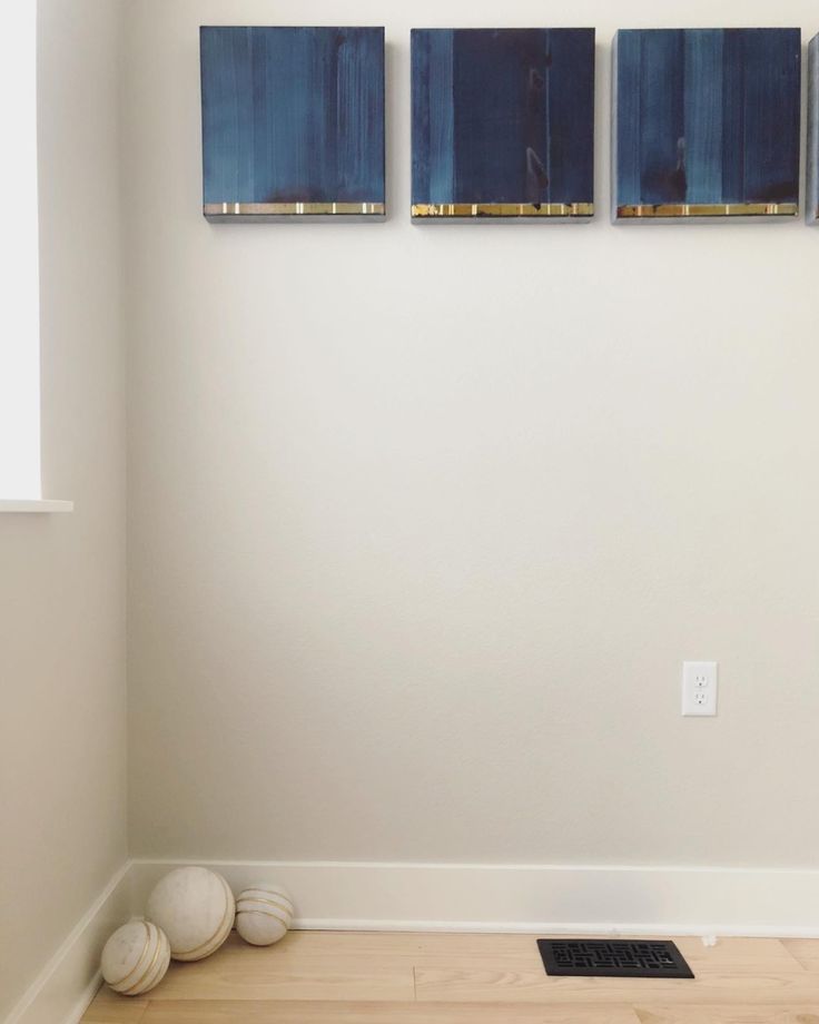 three paintings are hanging on the wall next to a radiator in an empty room