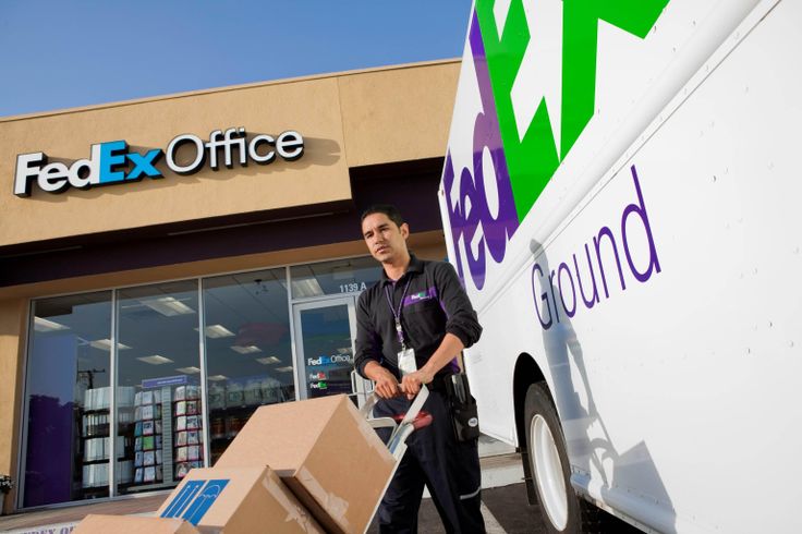 a fed ex office moving boxes into the back of a delivery truck for his move