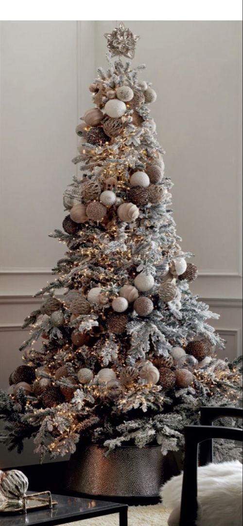 a decorated christmas tree in a living room with white and silver ornaments on the top