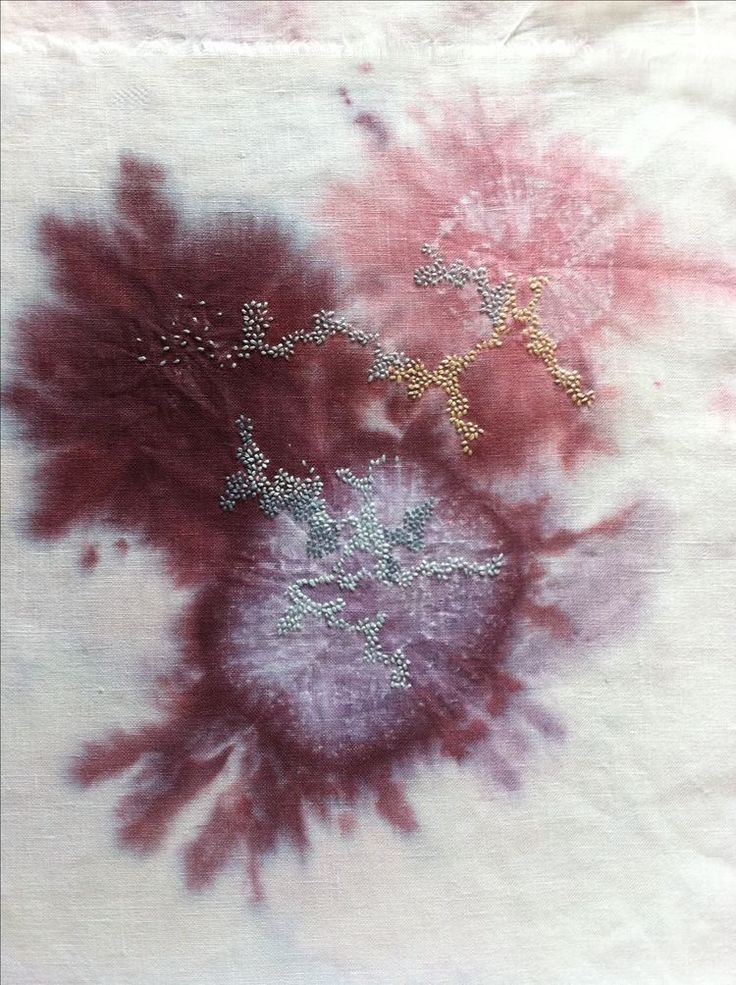 two red and white flowers are in the middle of a tie - dye pattern on a piece of cloth