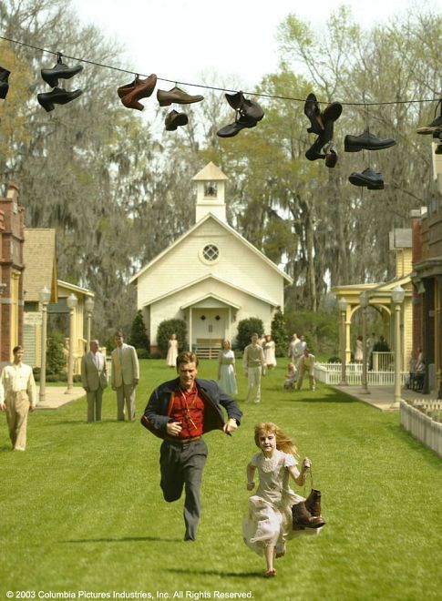 two people running in the grass with shoes hanging above them