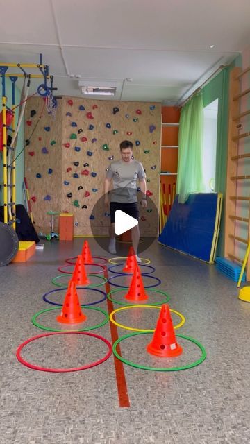 a man standing in front of a climbing wall surrounded by orange and green plastic cones