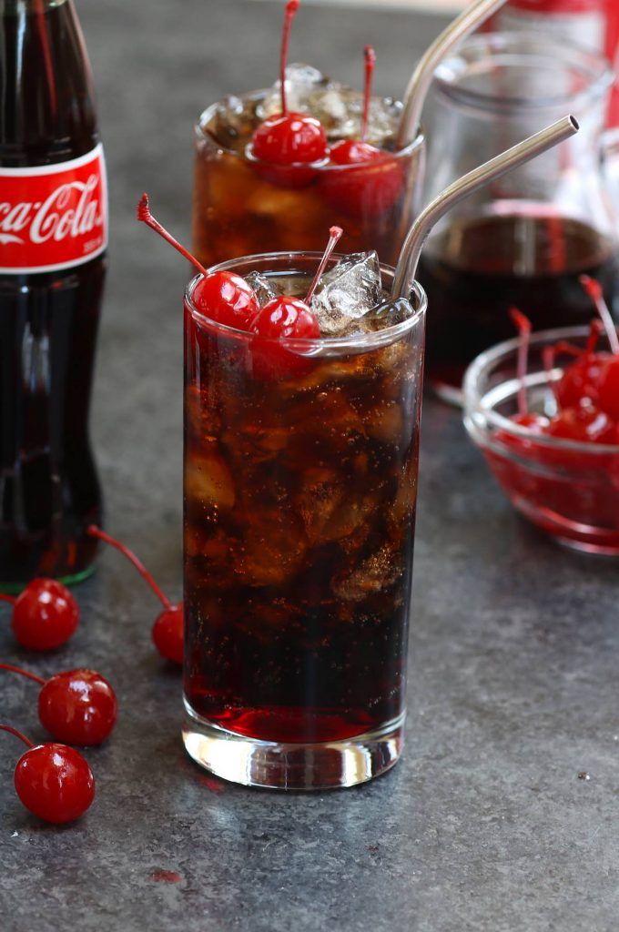 two glasses filled with coke and cherries